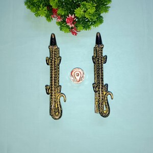 Peut inclure: Deux poignées de porte décoratives noires et dorées en forme de lézards. Les poignées présentent un motif détaillé de cercles et de lignes.