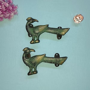 May include: Two peacock-shaped door handles with a green and gold finish. The handles are made of metal and have a traditional design.