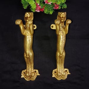 Peut inclure: Une paire de poignées de porte en métal doré en forme de tigres. Les poignées sont détaillées avec des rayures de tigre et ont un design en relief sur la base.