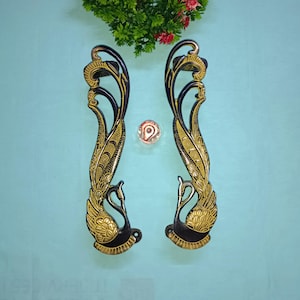 May include: A pair of ornate door handles with a peacock design. The handles are made of metal and have a black and gold finish.