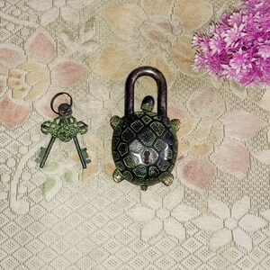 May include: A green turtle-shaped padlock with a keyhole and a matching key. The padlock is made of metal and has a black and green design.