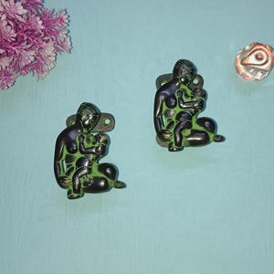 Puede incluir: Dos llamadores de puerta de metal verde y negro con forma de madre e hijo. La madre sostiene al niño en sus brazos.