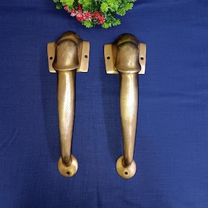 May include: Two antique brass door handles with a decorative design. Each handle features a raised, stylised elephant head with a VW logo on the forehead.