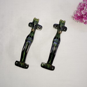 May include: A pair of black and green metal door handles with a horse head design. The handles are made of brass and have a polished finish.