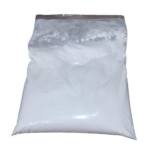 Peut inclure: Un sac en plastique transparent rempli d'une substance blanche et poudreuse. Le sac est scellé en haut avec une bande argentée. Le contenu semble être une poudre fine, remplissant la majeure partie du sac.