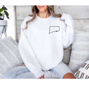 May include: White sweatshirt with a black outline of a speech bubble with the text "_2023" inside.