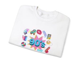 May include: White t-shirt with a colorful graphic design featuring the text "90's Kid" surrounded by images of 90s pop culture icons like roller skates, a slinky, a cassette tape, a phone, a game console, and a tamagotchi.