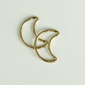 May include: Two gold crescent moon shaped hoops.