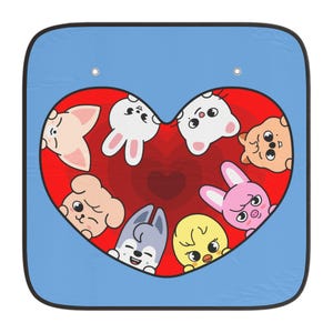 Op de afbeelding: Blauw auto-zonnescherm met een rood hart gevuld met cartoon-dierengezichten. De dieren zijn onder meer een varken, een konijn, een beer, een hond en een kuiken. Het zonnescherm heeft twee oogjes om op te hangen.