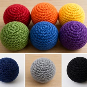 May include: A collection of handmade crochet balls in various colors, including red, orange, yellow, green, blue, purple, navy, gray, and black. The balls are arranged on a light brown wooden surface. Each ball has a textured, spherical shape.