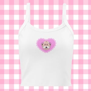 Könnte beinhalten: Weißes Spaghettiträger-Crop-Top mit einem rosafarbenen herzförmigen Design, das ein Comic-Gesicht mit einem Schnurrbart zeigt.