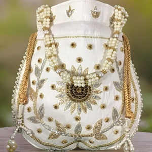 May include: White satin drawstring bag with a pearl and gold chain handle. The bag is decorated with gold and silver embroidery and a floral design.
