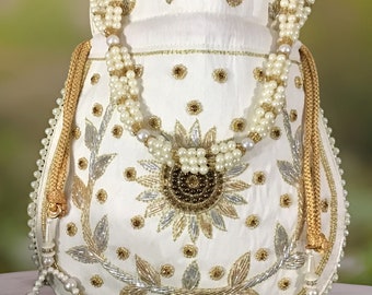 May include: White satin drawstring bag with a pearl and gold chain handle. The bag is decorated with gold and silver embroidery and a floral design.