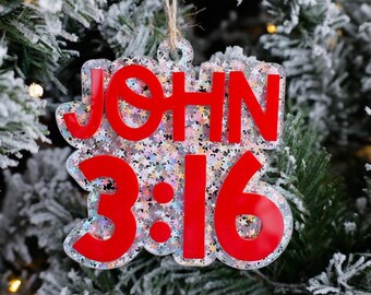 May include: A red glitter Christmas ornament with the text "JOHN 3:16" on a white background.