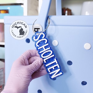 May include: A blue tote bag with white polka dots and a blue glitter keychain with the name "SCHOLTEN" in white letters.