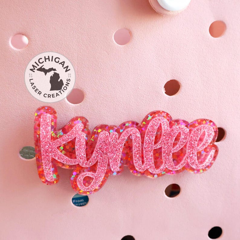 May include: Pink glitter name "Kynlee" with a Michigan Laser Creations logo in the background.