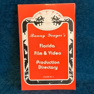 Könnte beinhalten: Ein roter Buchumschlag mit einer Schwarzweißillustration von Palmen und dem Text "Bunny Yeager's Florida Film & Video Production Directory Volume No. 2"