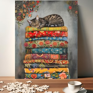 May include: A brown and tabby cat sleeps on a stack of colorful patterned fabric. The fabric is stacked high and the cat is curled up on top. The background is a light gray.