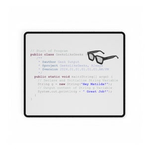 Op de afbeelding: Een rechthoekige witte muismat met een zwarte rand. De muismat bevat computercode en de tekst "GeeksLikeGeeks". Een afbeelding van een zwarte bril met de tekst "Geek Output" staat in de rechterbovenhoek.