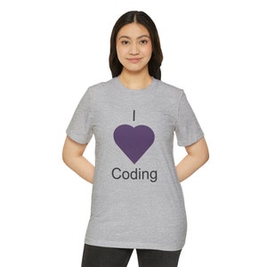 Op de afbeelding: Een grijs T-shirt met een paars hart en de tekst "Ik hou van coderen" gedrukt op de voorkant.