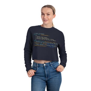 May include: A navy blue cropped sweatshirt with a code snippet printed on the front. The code snippet is written in a light blue, orange, and green font. The code snippet reads: //start of Program fauthor Geek Dutput @project GeekaLikesaks. Alway Prereton 0301.01.01.01.01.01/ phlic static void main(String[] args) //Declare and Initialize String Variable String new String( //Output content of String g Variable System.out.printing 1 See Your