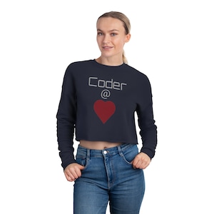 Puede incluir: Una sudadera corta azul marino con el texto "Coder @" y un gráfico de corazón rojo.