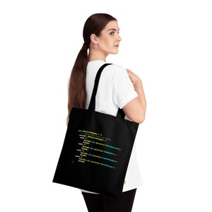 May include: A black tote bag with a white strap. The bag has a code snippet printed on it that reads: "let favoritePuppy = 3; switch (favoritePuppy) { case 1: system.out.println("Ballistic"); break; case 2: system.out.println("Thunderbolt"); break; case 3: system.out.println("Buttercup"); break; }"