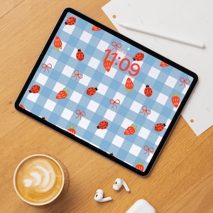Puede incluir: Una pantalla de iPad azul y blanco a cuadros vichy con un reloj digital que muestra las 11:09. La pantalla está decorada con fresas rojas y mariquitas.
