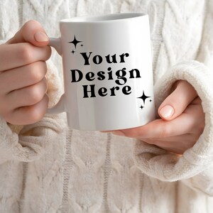 May include: White ceramic mug with a black handle. The mug has the text "Your Design Here" printed on it in a bold, black font. There are two small, black stars on either side of the text.