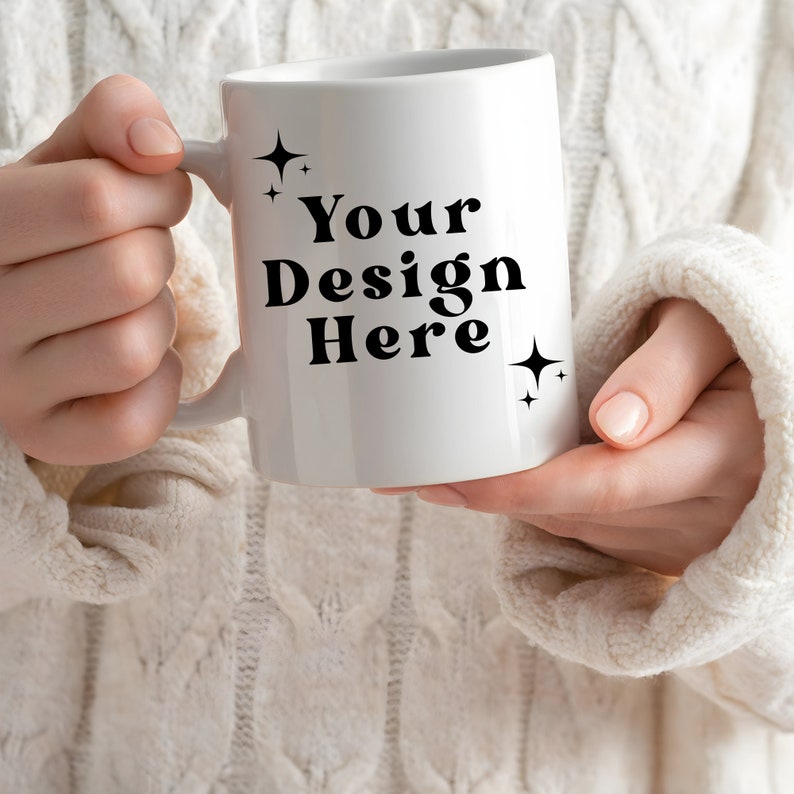 May include: White ceramic mug with a black handle. The mug has the text "Your Design Here" printed on it in a bold, black font. There are two small, black stars on either side of the text.