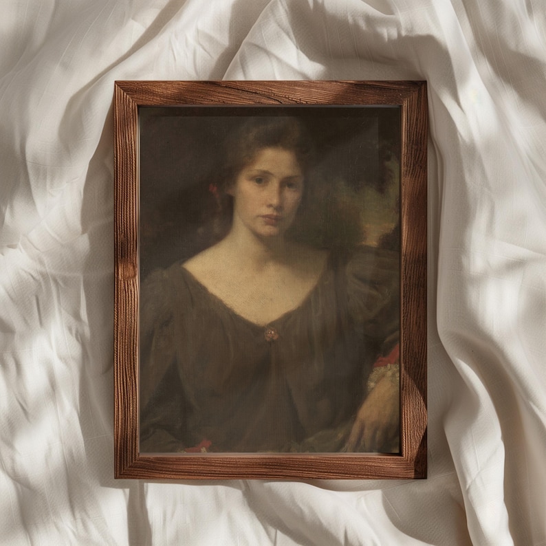 May include: A framed portrait of a woman in a brown dress. The artwork features a woman with long hair and a serious expression. The frame is made of wood and has a natural finish. The portrait is set against a white background.