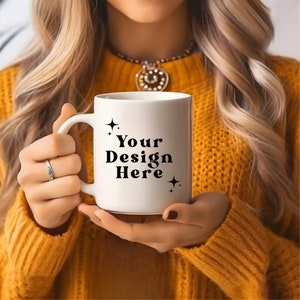 May include: A white ceramic mug with a black handle. The mug has the text "Your Design Here" printed on it with small stars on either side of the text.