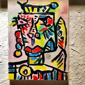 Puede incluir: Pintura abstracta de una cara con l&iacute;neas negras audaces, colores brillantes y una corona. La cara est&aacute; pintada en tonos de rosa, rojo, amarillo, verde y azul.