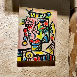 Puede incluir: Pintura abstracta de una cara con l&iacute;neas negras audaces y colores brillantes, incluyendo rojo, amarillo, azul, verde y rosa. La cara est&aacute; rodeada de un fondo blanco.