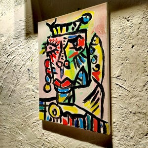 Puede incluir: Pintura abstracta de una cara con l&iacute;neas negras audaces, colores brillantes y una corona. La cara est&aacute; pintada en tonos de rosa, amarillo, azul, verde y rojo.