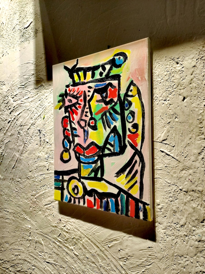 Puede incluir: Pintura abstracta de una cara con l&iacute;neas negras audaces, colores brillantes y una corona. La cara est&aacute; pintada en tonos de rosa, amarillo, azul, verde y rojo.