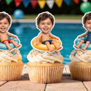 May include: Three cupcakes topped with custom photo cake toppers featuring a child's face on a cartoon body sitting in an inflatable pool ring. The cupcakes have white frosting decorated with colorful sprinkles and small seashell accents.