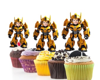 May include: Yellow and black robot cupcake toppers with a child's face on the robot's head. The toppers are on top of cupcakes with different colored frosting.