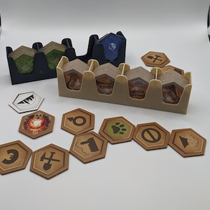 Könnte beinhalten: Ein beigefarbener Plastik-Organizer mit sechs Fächern zum Verstauen von Spielsteinen. Der Organizer ist gefüllt mit kleinen, braunen sechseckigen Spielsteinen mit verschiedenen Symbolen. Auf einer weißen Oberfläche liegen auch mehrere lose Spielsteine.