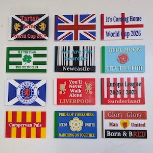 May include: A collection of twelve rectangular plastic signs featuring various sports-themed designs, including flags, team logos, and text such as Tartan Army World Cup 2026, It's Coming Home, We Are The Geordies, Blue Moon, and Glory Glory Man United.