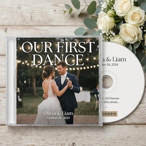 May include: A CD case and disc with a wedding theme. The case reads "OUR FIRST DANCE" with the couple's names and date. The disc has the couple's names and date, with song titles and a scannable code. White roses and greenery are in the background.
