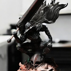 Puede incluir: Una figura de acci&oacute;n negra y plateada de un guerrero con una gran espada y una capa. La figura est&aacute; de pie sobre una base con una calavera y otros detalles. La figura est&aacute; hecha de pl&aacute;stico y mide aproximadamente 25 cm de alto.