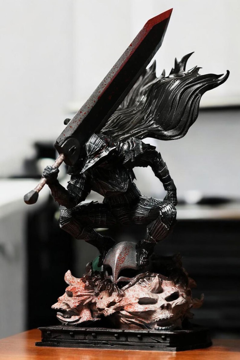 Puede incluir: Una figura de acci&oacute;n negra y plateada de un guerrero con una gran espada y una capa. La figura est&aacute; de pie sobre una base con una calavera y otros detalles. La figura est&aacute; hecha de pl&aacute;stico y mide aproximadamente 25 cm de alto.