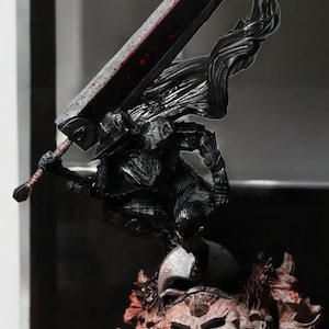 Puede incluir: Una figura detallada de un guerrero sosteniendo una gran espada, de pie sobre una calavera con una base. La figura es negra y roja.
