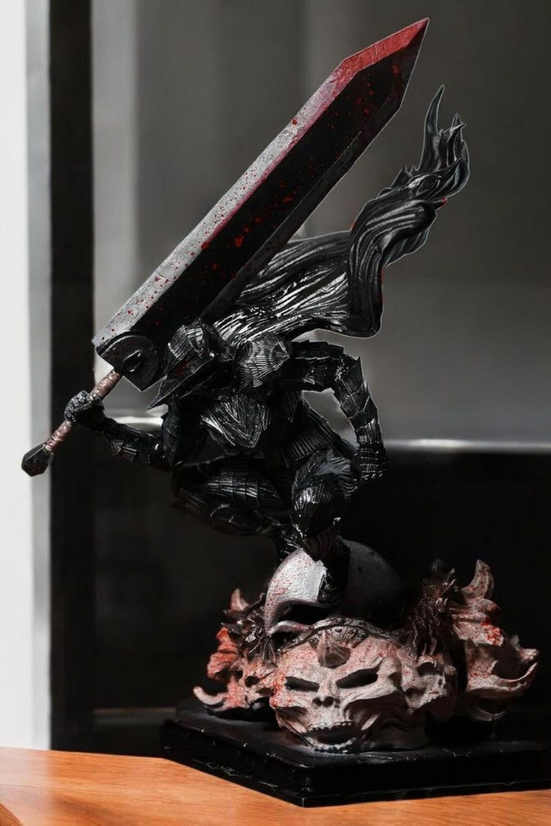 Puede incluir: Una figura detallada de un guerrero sosteniendo una gran espada, de pie sobre una calavera con una base. La figura es negra y roja.