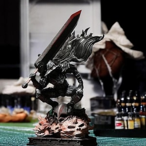 Puede incluir: Una figura detallada de un personaje de la serie de anime Berserk. El personaje sostiene una espada grande y est&aacute; de pie sobre una base con cr&aacute;neos.