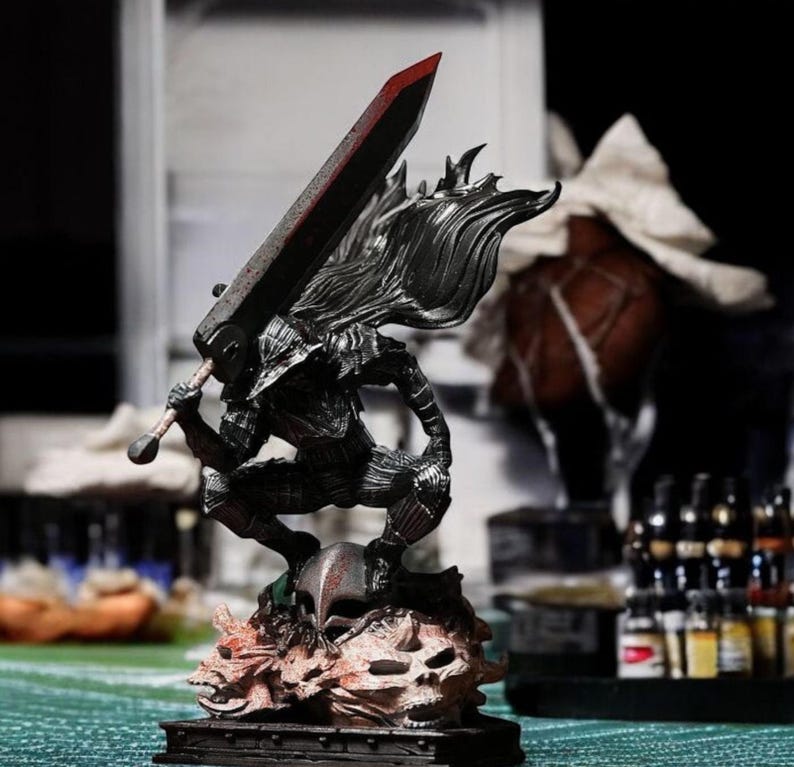 Puede incluir: Una figura detallada de un personaje de la serie de anime Berserk. El personaje sostiene una espada grande y est&aacute; de pie sobre una base con cr&aacute;neos.