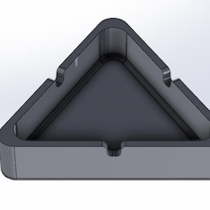 Può includere: Un posacenere di forma triangolare realizzato in materiale grigio scuro. Il posacenere ha una base larga e poco profonda e un bordo rialzato.