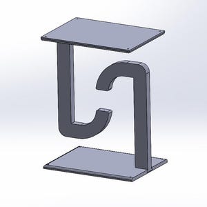 May include: A gray, geometric headphone stand with a rectangular base and top, connected by a curved support. The stand is designed to hold headphones, with a modern and minimalist aesthetic.