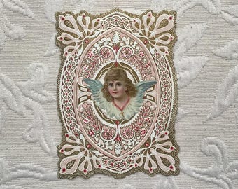 Puede incluir: Una tarjeta de San Valentín antigua con un diseño delicado y ornamentado, con una imagen central de un ángel con alas. El ángel tiene un halo y está rodeado de flores rosas y blancas.
